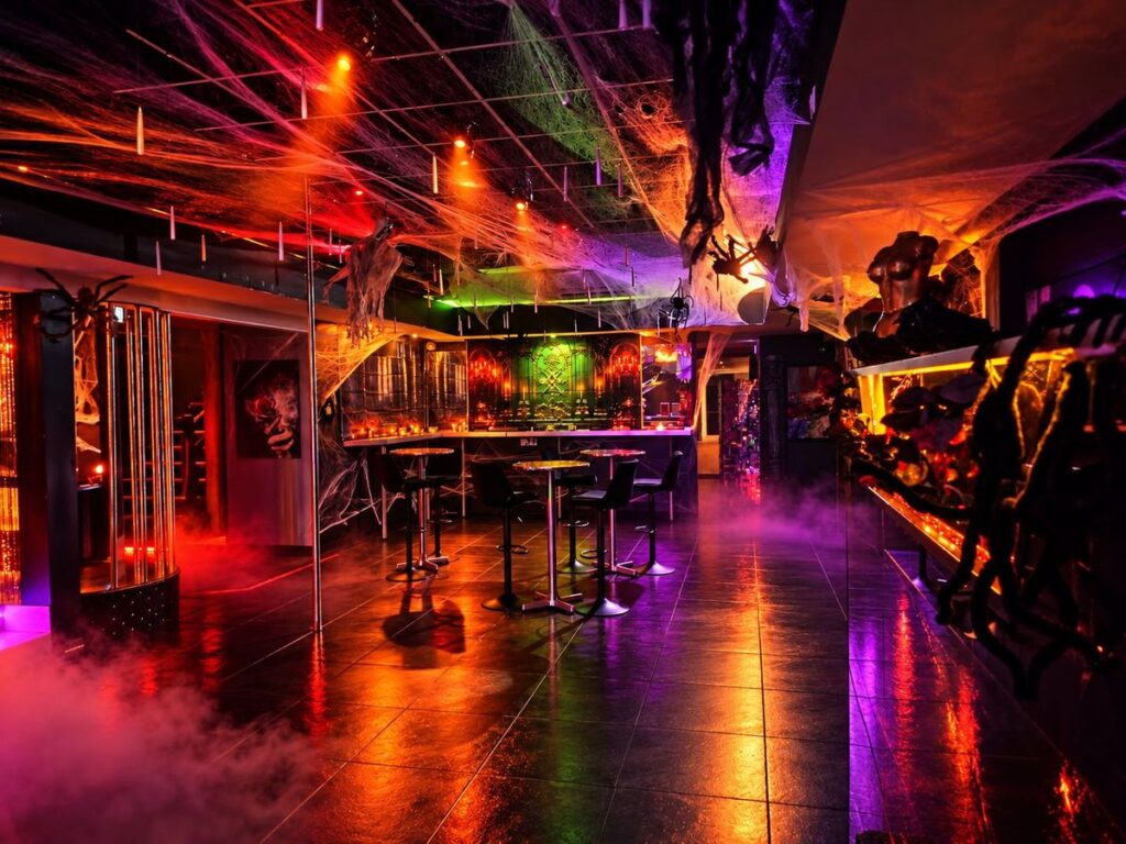 Salle principale du Privé Toulouse décorée pour la soirée Les Délices de l’Enfer : toiles d’araignée, brume et lumières rouges et violettes