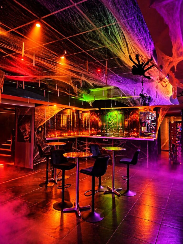 Coin bar gothique baigné de lumières orange et violettes
