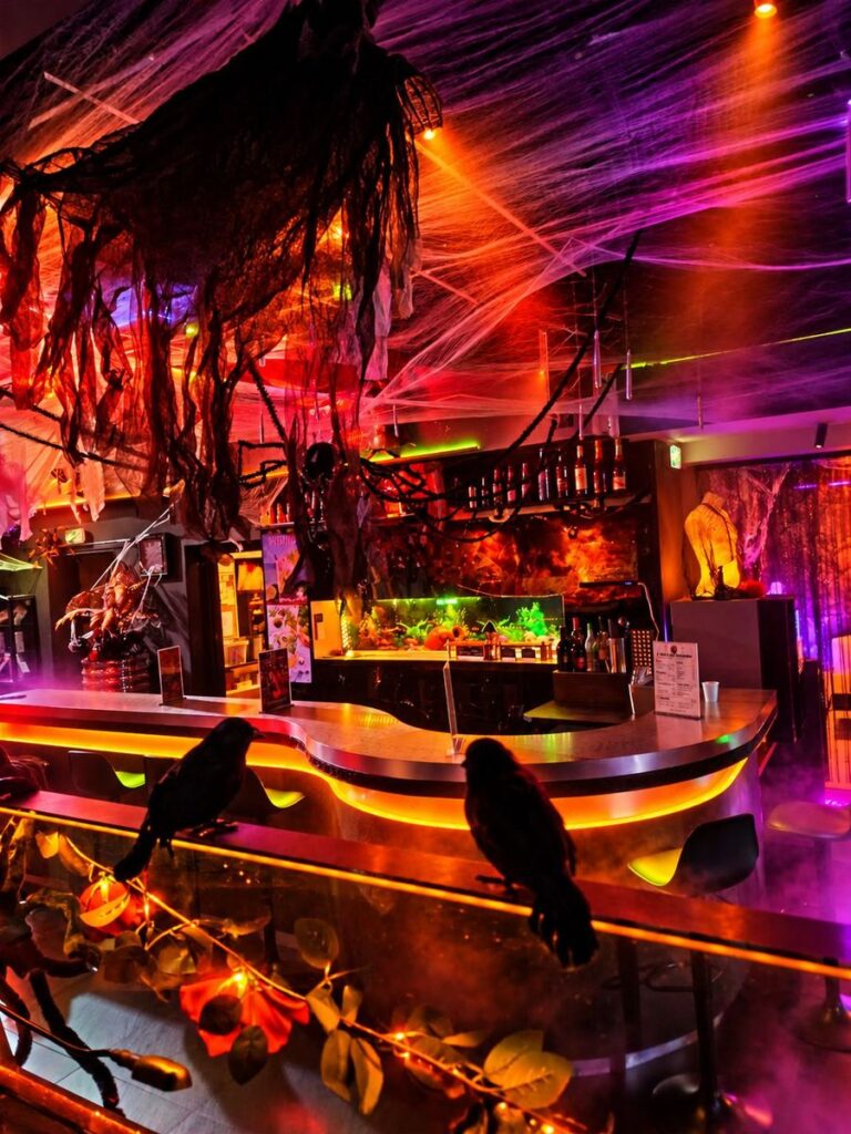 Corbeaux sur le comptoir du bar éclairé, décor d’Halloween du Privé
