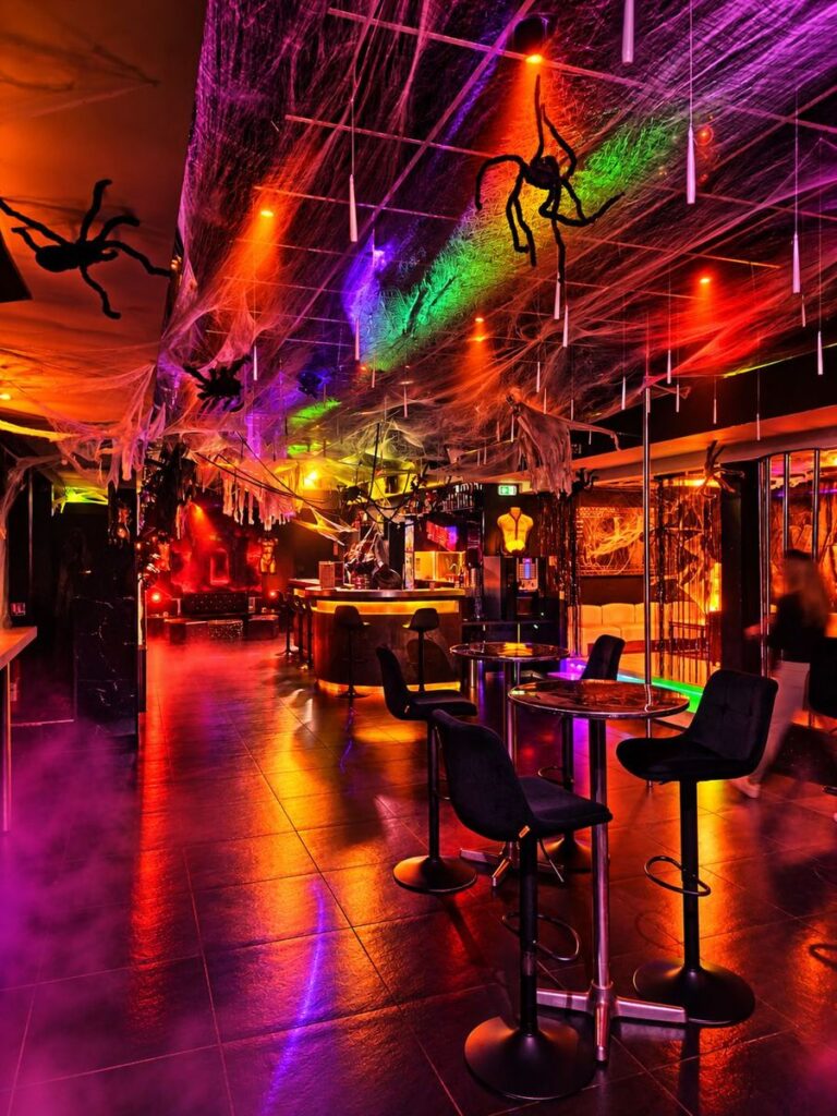 Salle et bar du Privé plongés dans la brume et les lumières de l’Enfer